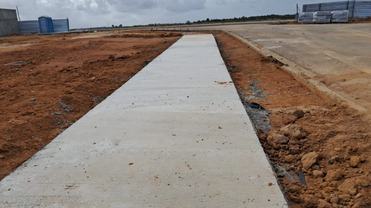 Trecho de calçada concluído, entre a via e os lotes.